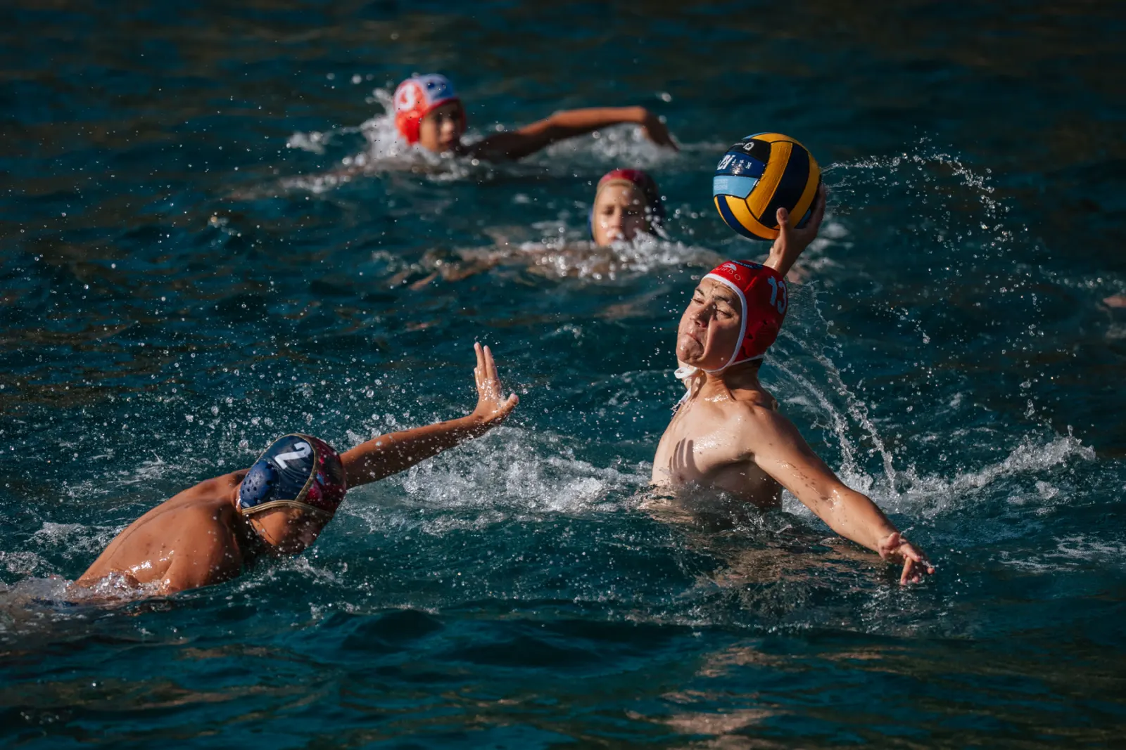 Players battling for the ball in the sea at sunset